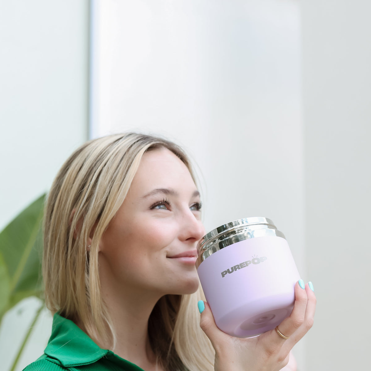 A woman holding an open lilac PurePop Food Flask.