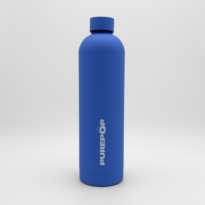 An Ultra Marine blue Core Series Plus reusable water bottle, featuring the PUREPOP logo printed vertically in white, stands upright against a plain white background. This insulated flask boasts a double-walled stainless steel construction to keep beverages cold for hours and is fully leakproof for worry-free hydration on the go.