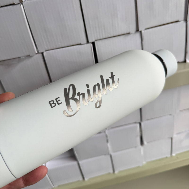 White PurePop flask engraved with the Be Bright logo.