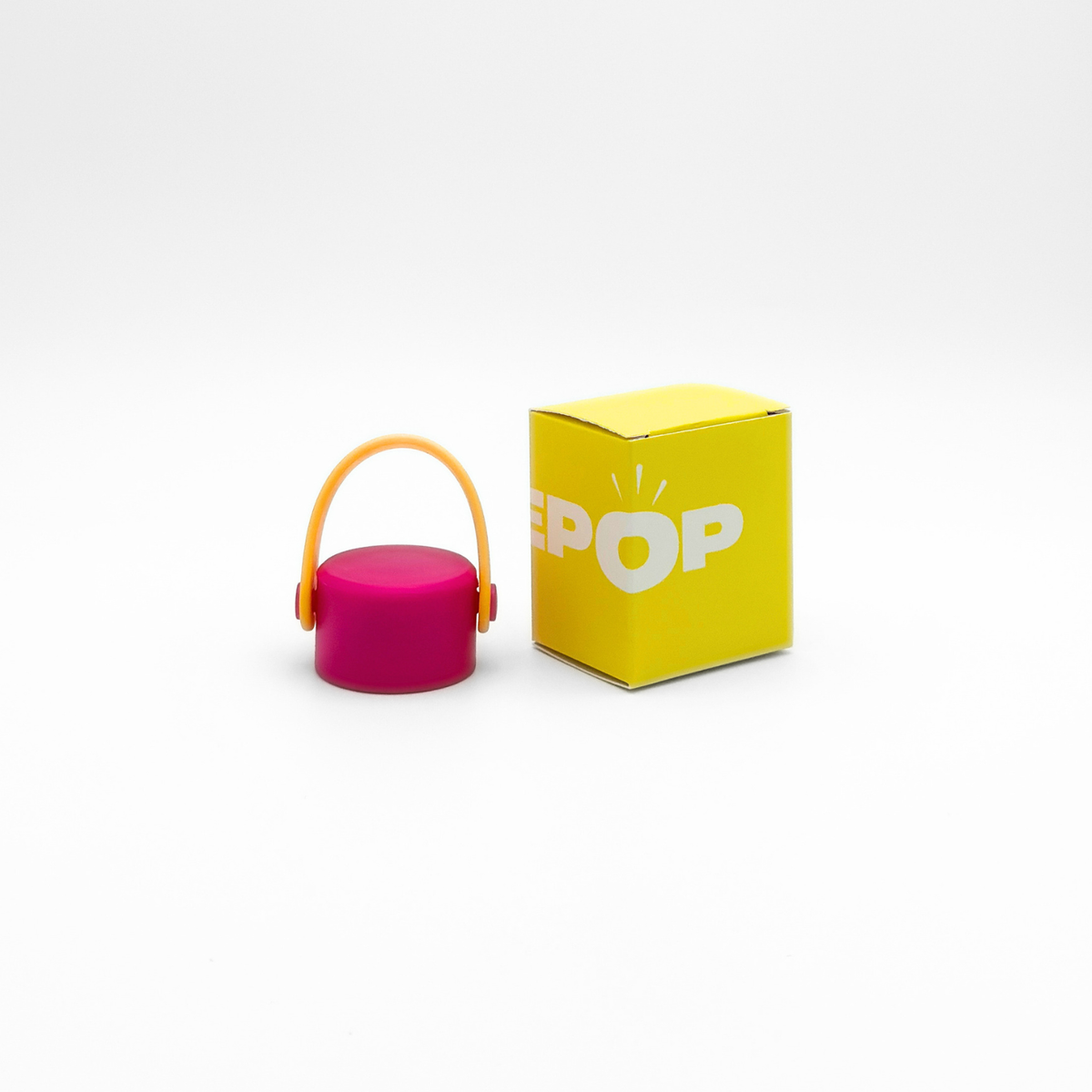 A compact, round Core Series flask in magenta with a gold carry lid and a leakproof seal is placed next to a yellow box labeled PUREPOP on a plain white background.