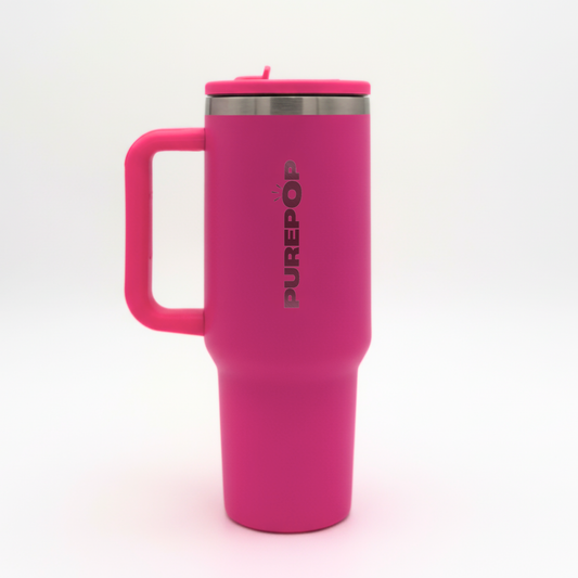 The PurePop™ Carry Series | Hot Pink is a stylish, bright pink insulated travel mug with a handle and silver lid. "PUREPOP" is printed vertically on the side in bold black letters. Perfect for on-the-go use, it stands upright against a white background.