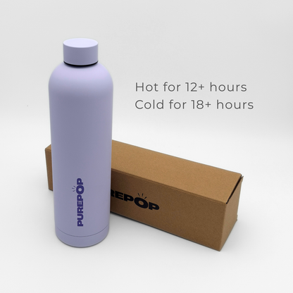 A pastel lilac Core Series Plus insulated flask stands beside a brown box. Text reads: Hot for 12+ hours, Cold for 18+ hours. The double-walled stainless steel bottle features a screw cap and minimalist design against a white background.