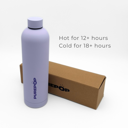 A pastel lilac insulated bottle from the Core Series Plus collection, crafted from double-walled stainless steel and labeled PUREPOP, stands beside a brown box. Text reads: Hot for 12+ hours, Cold for 18+ hours. This leakproof flask is set against a plain white background.