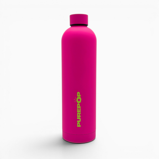 A blush magenta Core Series Plus reusable water bottle with a matching cap stands upright, featuring the word PUREPÖP printed vertically in yellow-green letters on the front. The background is plain white.