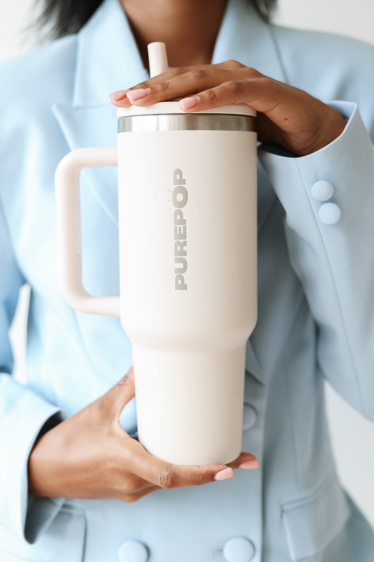 A woman in a white blazer holding a turquoise PurePop Carry Series tumbler with a handle and straw.