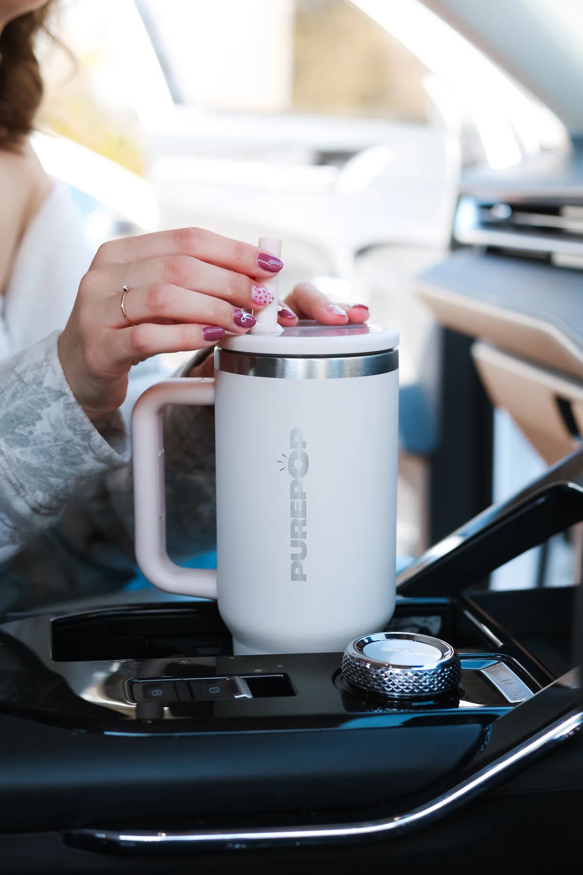 A PurePop Carry Series tumbler with a handle and straw, held in a car.
